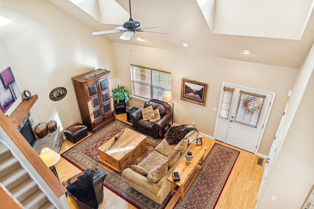 living room featuring ceiling fan, high vaulted ceiling, and wood-type flooring