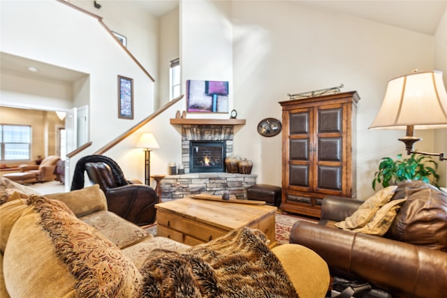 living room featuring high vaulted ceiling and a stone fireplace