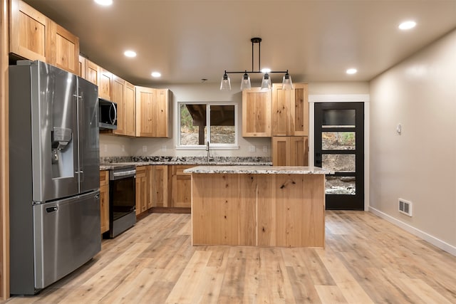 kitchen featuring stainless steel appliances, a center island, pendant lighting, and light wood-type flooring