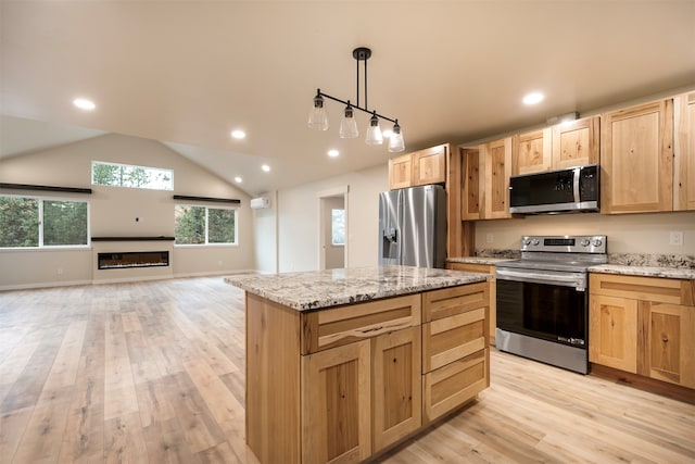 kitchen featuring stainless steel appliances, decorative light fixtures, a center island, and light hardwood / wood-style flooring