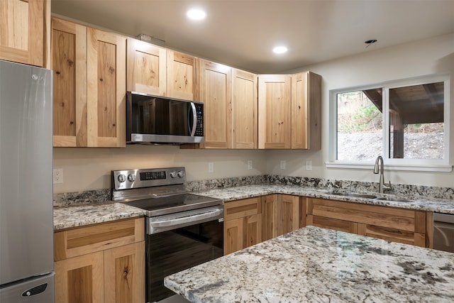 kitchen with light stone counters, sink, light brown cabinets, and appliances with stainless steel finishes