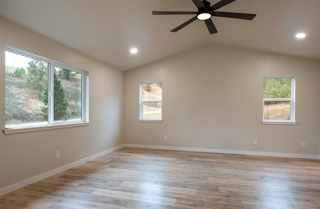 empty room featuring ceiling fan, lofted ceiling, a wealth of natural light, and light hardwood / wood-style floors