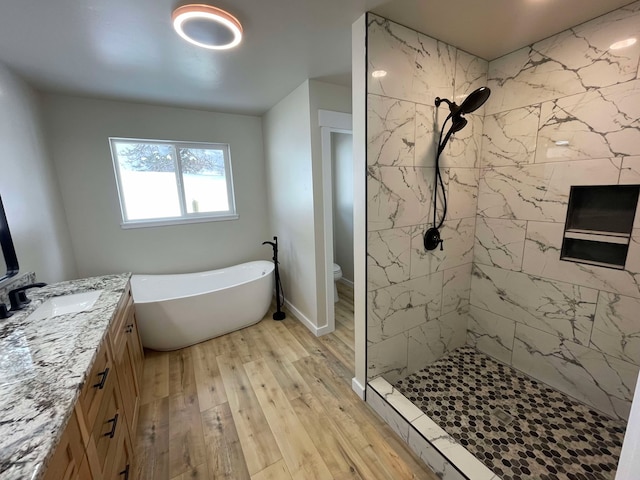 full bathroom featuring independent shower and bath, wood-type flooring, vanity, and toilet