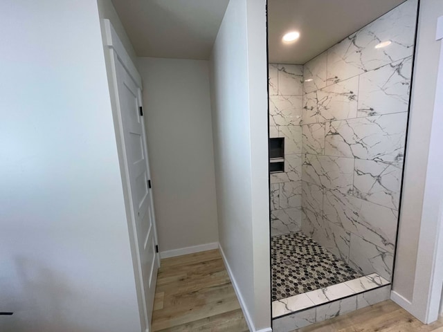 bathroom with hardwood / wood-style floors and a tile shower