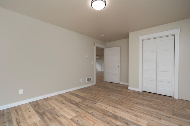 unfurnished bedroom with light wood-type flooring and a closet