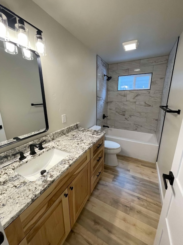 full bathroom with vanity, toilet, tiled shower / bath combo, and hardwood / wood-style floors