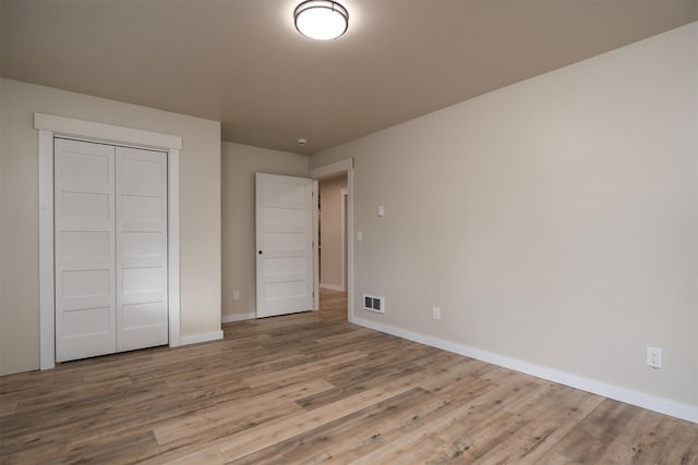 unfurnished bedroom featuring light hardwood / wood-style flooring and a closet