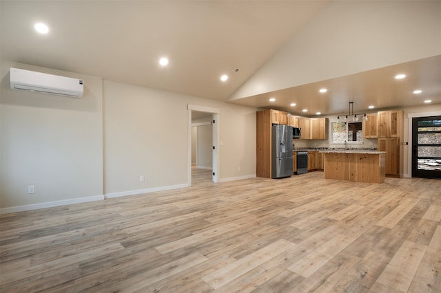 kitchen featuring pendant lighting, light hardwood / wood-style flooring, appliances with stainless steel finishes, a kitchen island, and an AC wall unit