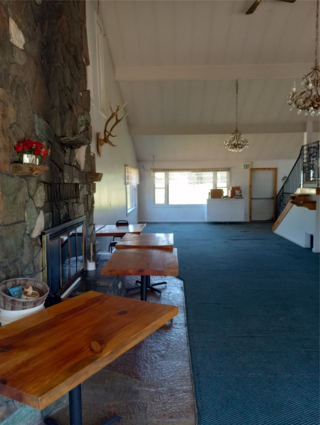 living room featuring dark colored carpet, beam ceiling, high vaulted ceiling, and a stone fireplace