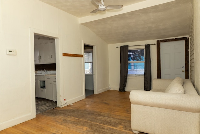 living room with hardwood / wood-style floors, vaulted ceiling, ceiling fan, and sink