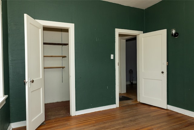 unfurnished bedroom featuring a spacious closet, wood-type flooring, and a closet