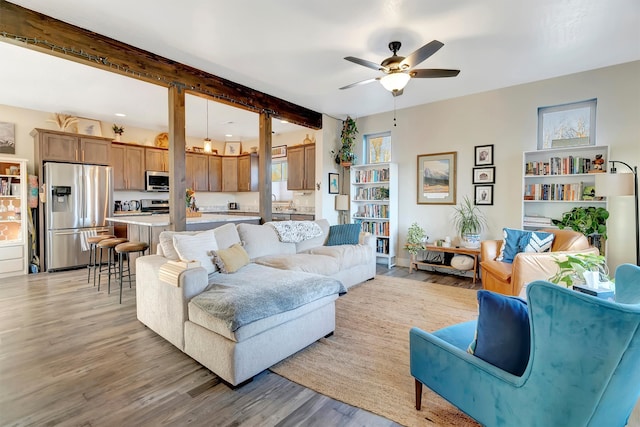 living room with beamed ceiling, light wood-type flooring, and ceiling fan