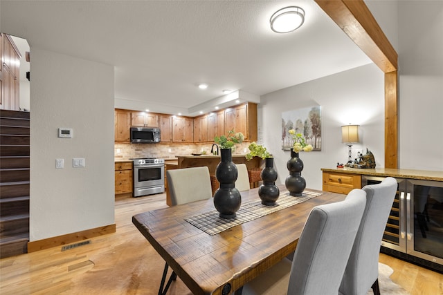 dining area featuring light hardwood / wood-style floors, wine cooler, and wet bar