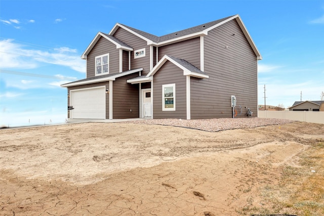 view of front of house featuring roof with shingles, a garage, and fence