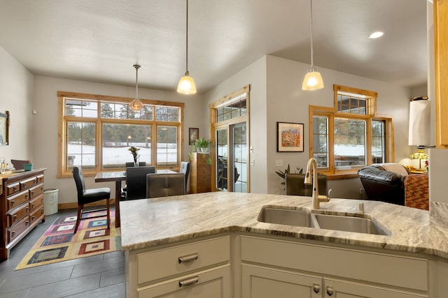 kitchen with sink, light stone counters, and decorative light fixtures