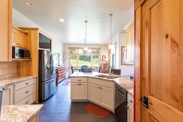 kitchen with sink, decorative light fixtures, light stone countertops, and appliances with stainless steel finishes