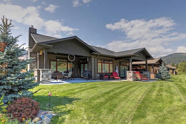 back of property featuring a patio, a mountain view, and a lawn