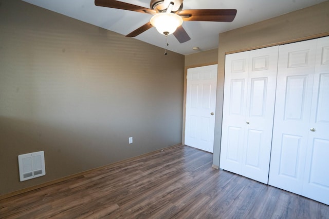 unfurnished bedroom featuring a closet, dark hardwood / wood-style floors, and ceiling fan