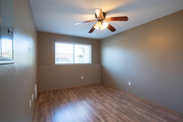 empty room with ceiling fan and dark hardwood / wood-style flooring