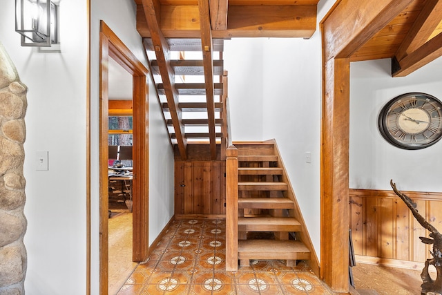 stairway with tile patterned flooring, beam ceiling, and wooden walls