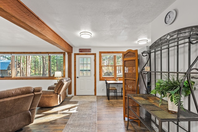 foyer entrance featuring beam ceiling, wood-type flooring, and a textured ceiling