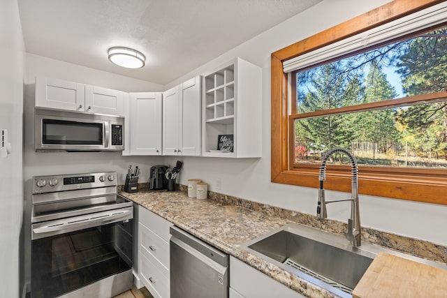 kitchen with white cabinets, light stone counters, sink, and stainless steel appliances