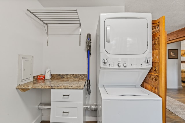 laundry area with cabinets, wood-type flooring, and stacked washer and dryer