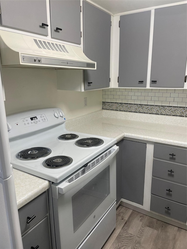 kitchen with gray cabinetry, white electric range oven, extractor fan, decorative backsplash, and light wood-type flooring