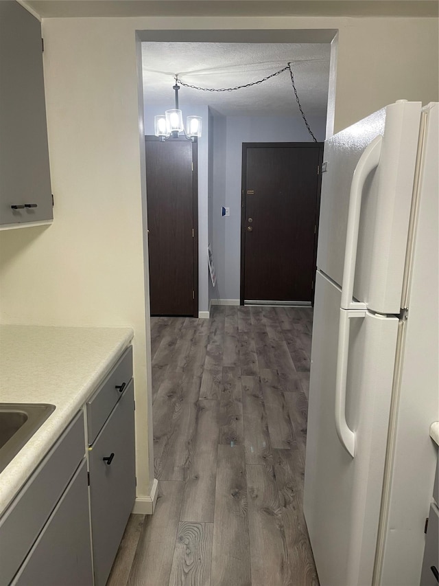 kitchen with a textured ceiling, white refrigerator, an inviting chandelier, hardwood / wood-style floors, and hanging light fixtures