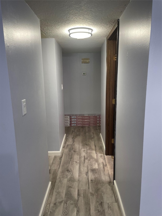 hall featuring light hardwood / wood-style floors and a textured ceiling