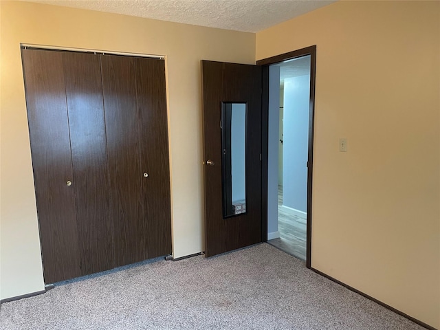 unfurnished bedroom featuring light carpet, a closet, and a textured ceiling