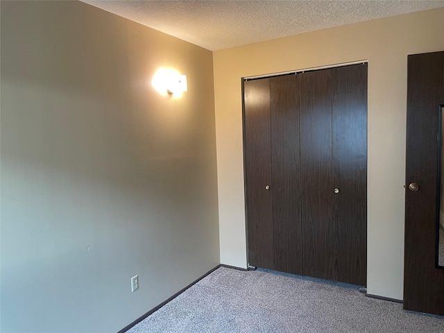 unfurnished bedroom featuring a closet, light colored carpet, and a textured ceiling