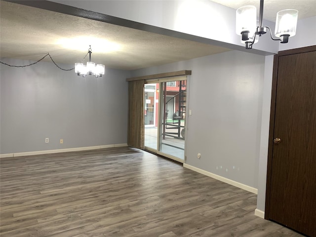 unfurnished dining area featuring a textured ceiling, an inviting chandelier, and dark wood-type flooring