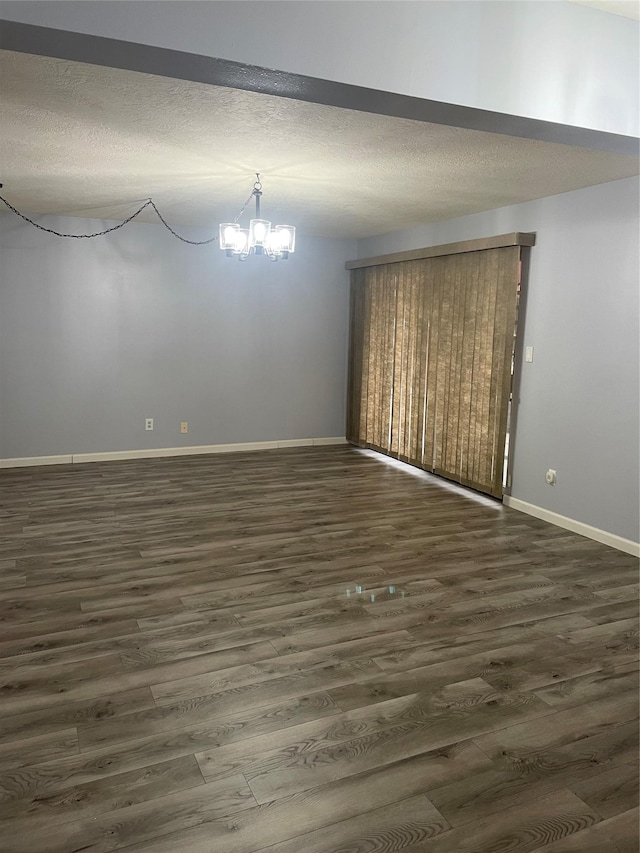 unfurnished dining area featuring a chandelier, a textured ceiling, and dark hardwood / wood-style floors