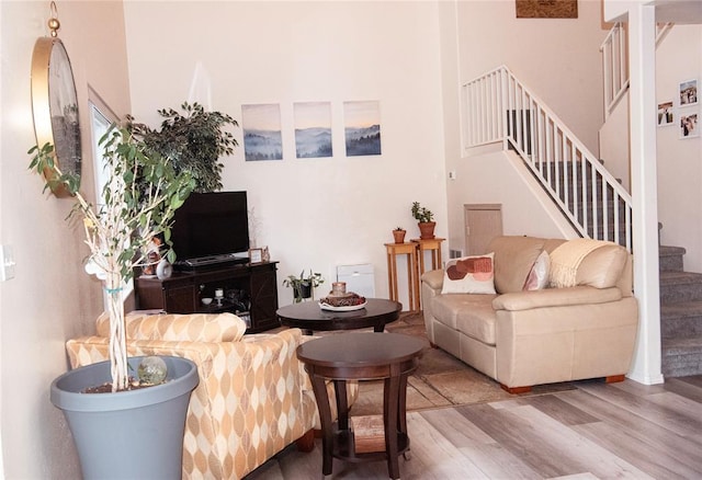 living room with wood-type flooring and a towering ceiling