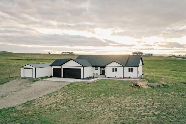 view of front of house with a lawn, a garage, and a rural view