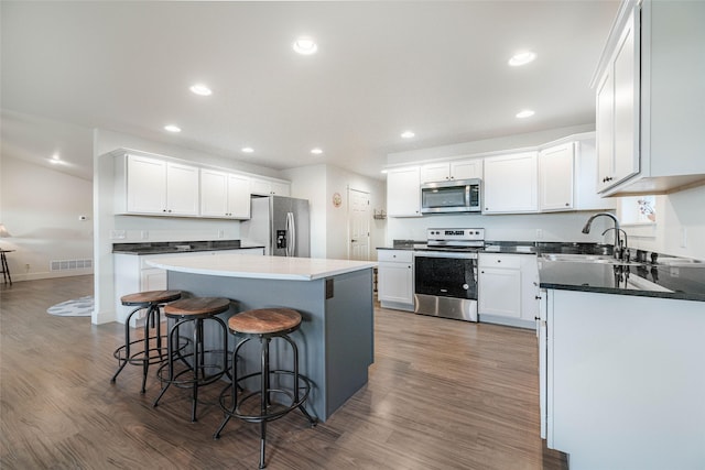 kitchen featuring a breakfast bar, white cabinets, a kitchen island, dark hardwood / wood-style flooring, and stainless steel appliances