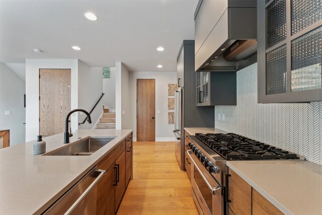 1148 Glades Dr, Whitefish, MT 59937 - kitchen with stainless steel appliances, custom exhaust hood, light wood-style flooring, light countertops, and tasteful backsplash