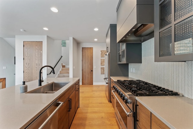1148 Glades Dr, Whitefish, MT 59937 - kitchen featuring tasteful backsplash, high end appliances, wall chimney range hood, sink, and light hardwood / wood-style floors