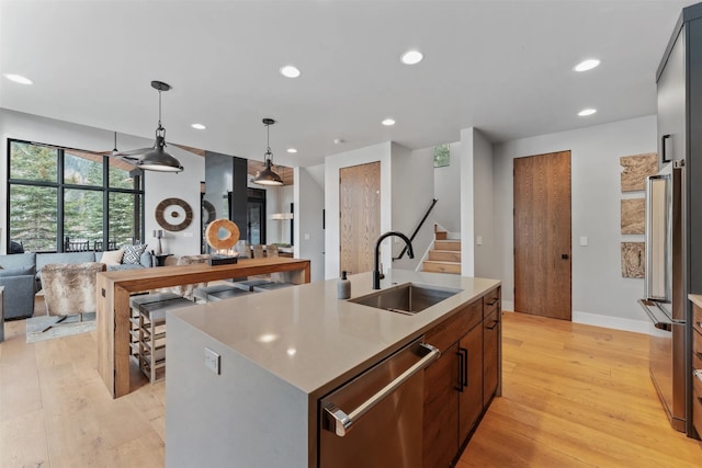 1148 Glades Dr, Whitefish, MT 59937 - kitchen with dishwasher, sink, pendant lighting, light hardwood / wood-style floors, and a kitchen island with sink