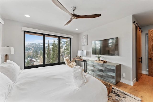 1148 Glades Dr, Whitefish, MT 59937 - bedroom with a barn door, ceiling fan, and light wood-type flooring