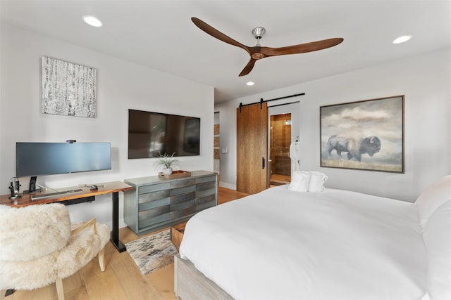 1148 Glades Dr, Whitefish, MT 59937 - bedroom with connected bathroom, a barn door, ceiling fan, and light hardwood / wood-style flooring