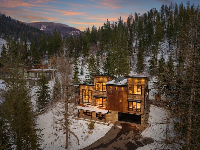 snow covered rear of property featuring a mountain view and a garage