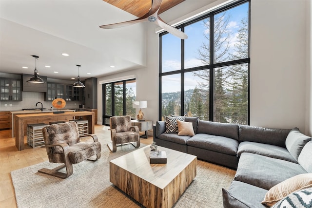 1148 Glades Dr, Whitefish, MT 59937 - living room featuring a towering ceiling, light wood-type flooring, ceiling fan, and sink