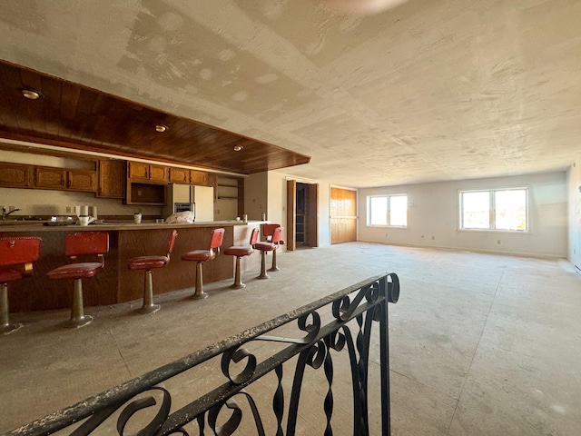 interior space with white fridge with ice dispenser and a breakfast bar area