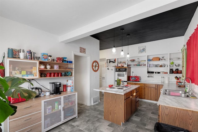 kitchen featuring a kitchen island, white appliances, sink, and hanging light fixtures