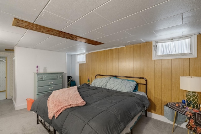 bedroom featuring light carpet and wooden walls