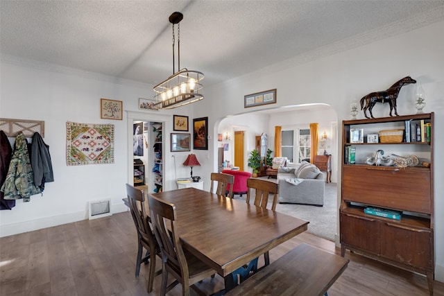 dining area featuring a notable chandelier, a textured ceiling, and hardwood / wood-style flooring