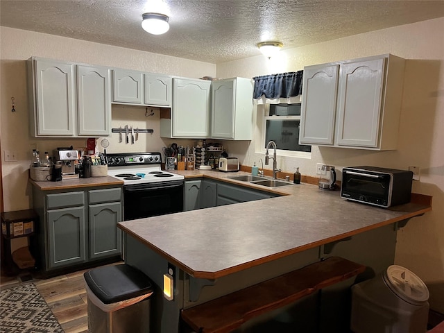 kitchen featuring kitchen peninsula, a textured ceiling, white range with electric stovetop, sink, and light hardwood / wood-style flooring