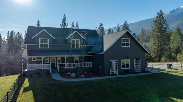 view of front of home featuring a mountain view, covered porch, and a front yard